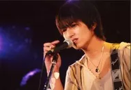 伊達晃二/ライブフォト・横型・バストアップ・衣装ベージュ・左向き・右手マイク・口開け・背景黒/生写真