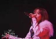 日笠陽子/ライブフォト・横型・バストアップ・衣装白・右手親指人差し指立て・左手マイク・ライト赤・背景黒/ライブツアー「Le Tour de Couleur」フォトチョイス